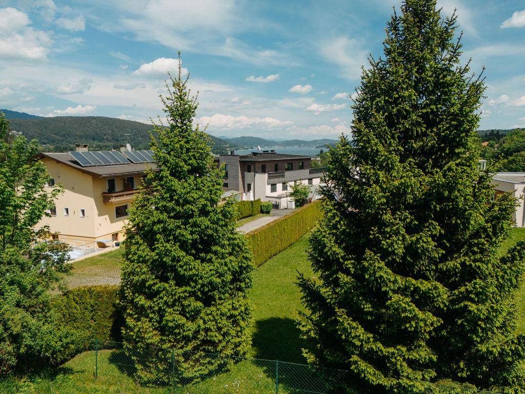 Blick über grüne Bäume auf Wohnhäuser und den See in der malerischen Landschaft.