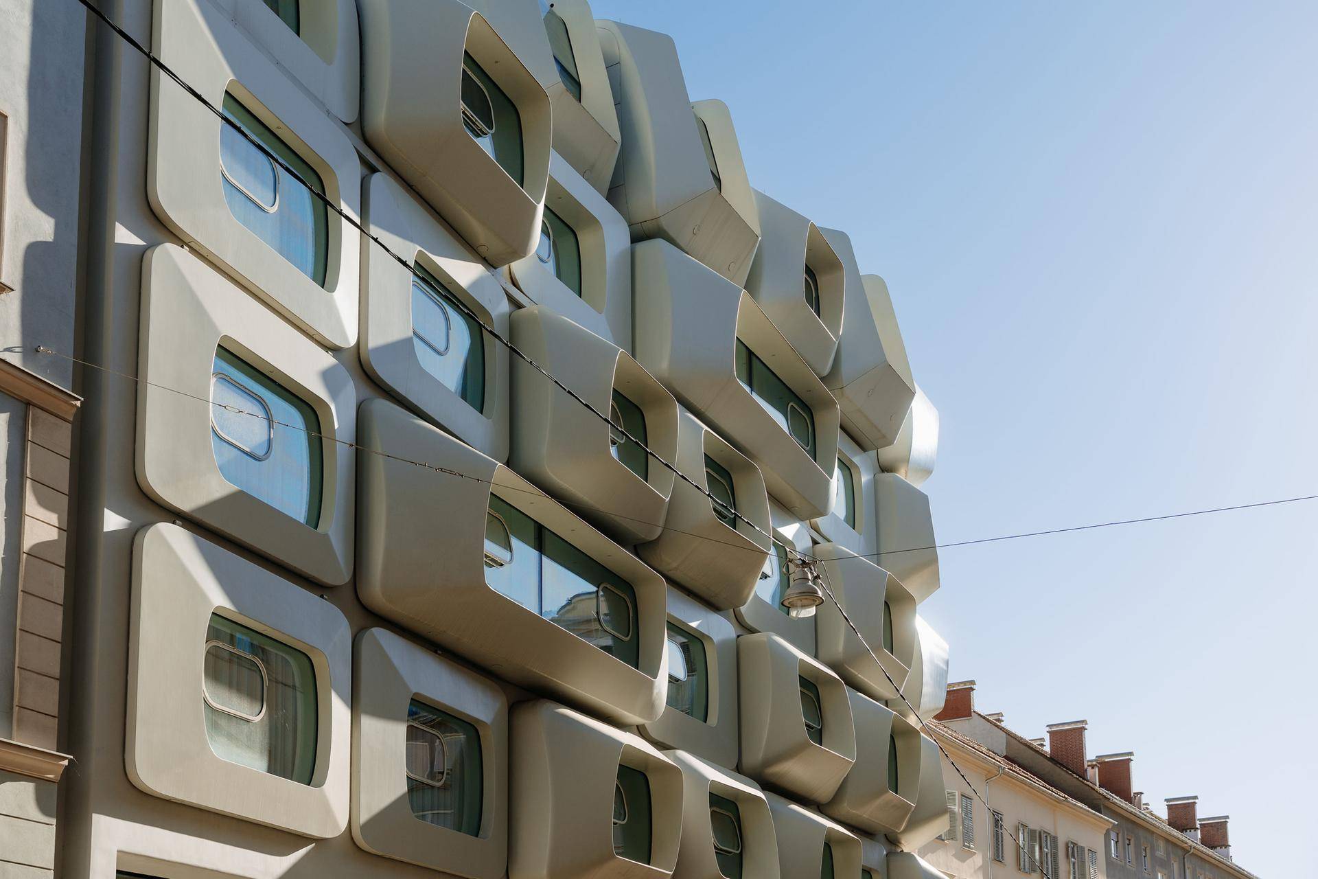 Auffällige moderne Architektur mit einer einzigartigen, organisch geformten Fassade und kleinen Fenstern.