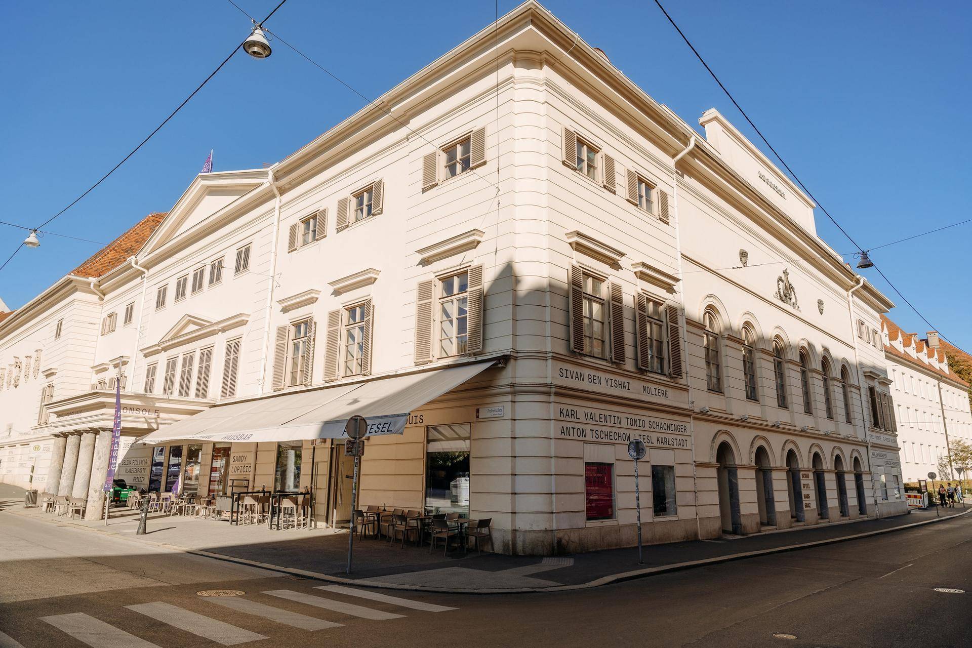 Elegantes historisches Gebäude mit einem Straßencafé und klassischen Fensterläden in der Stadt.