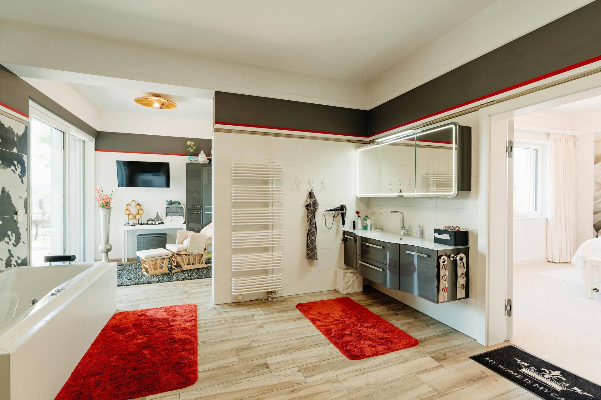Modernes Badezimmer mit Doppelwaschbecken, beheiztem Handtuchhalter und offener Gestaltung zum Schlafbereich.