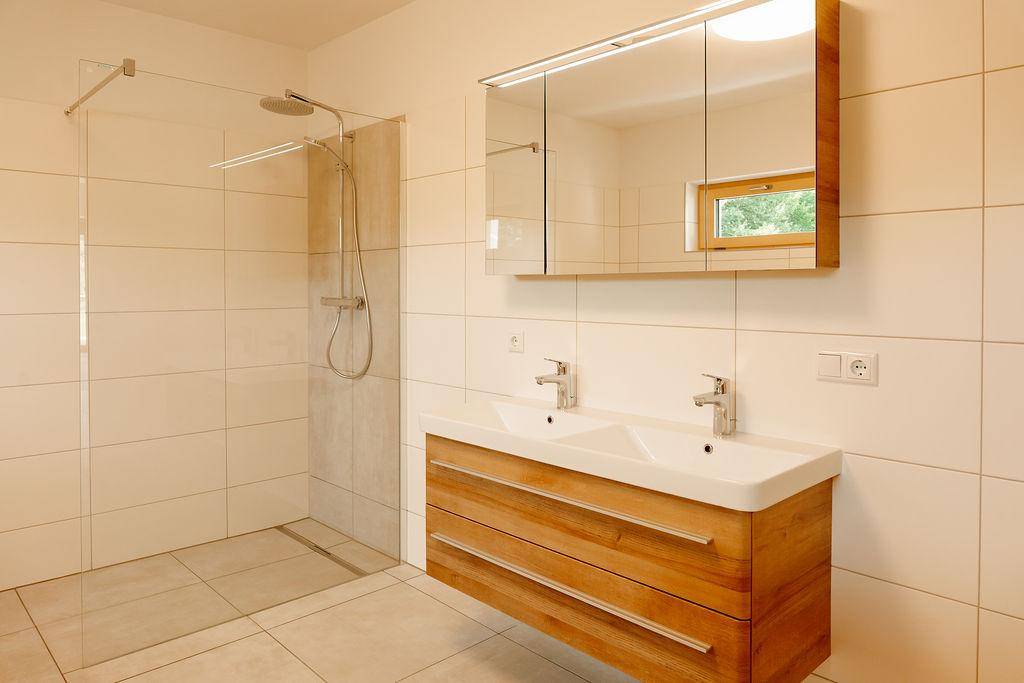 Modernes Badezimmer mit Doppelwaschbecken, begehbarer Dusche und Fenster für Tageslicht.