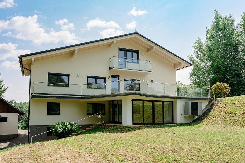 Modernes Haus mit weitläufiger Terrasse und direktem Zugang zum grünen Gartenbereich.