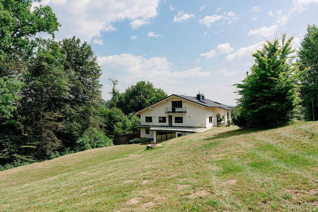 Freistehendes Haus in Hanglage mit weitem Blick über die grüne Landschaft und Wiesen.