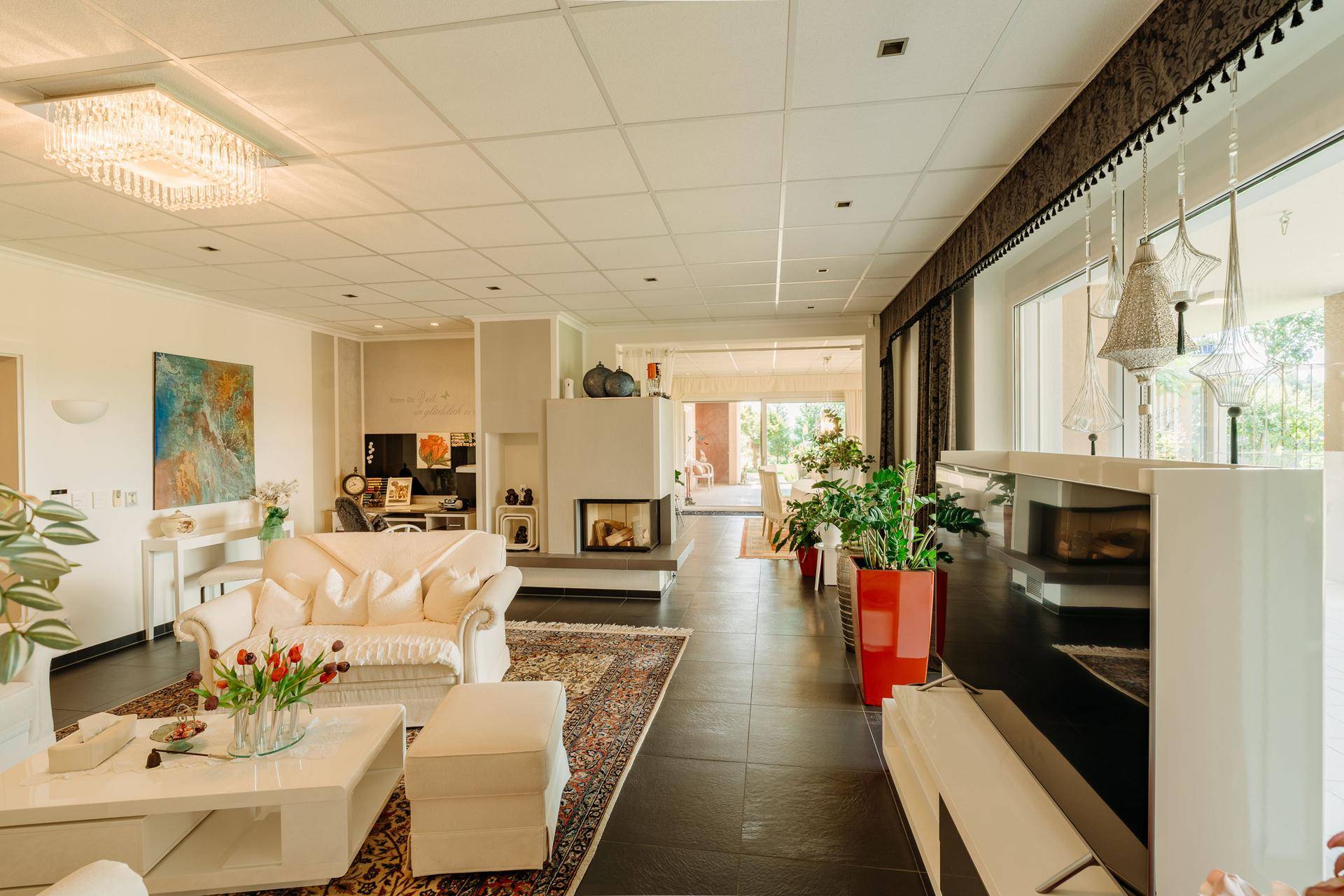 Großzügiges Wohnzimmer mit Kamin, bequemen Sofas und großen Fenstern, die viel Licht hereinlassen.