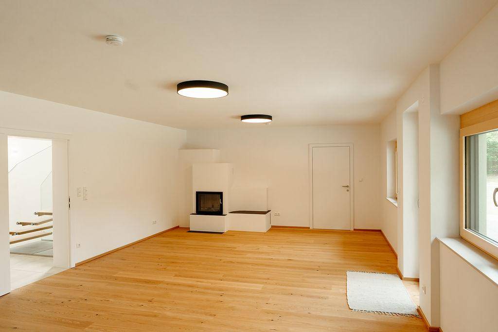 Geräumiges Wohnzimmer mit Holzboden und modernem Kamin, ideal für gemütliche Abende.