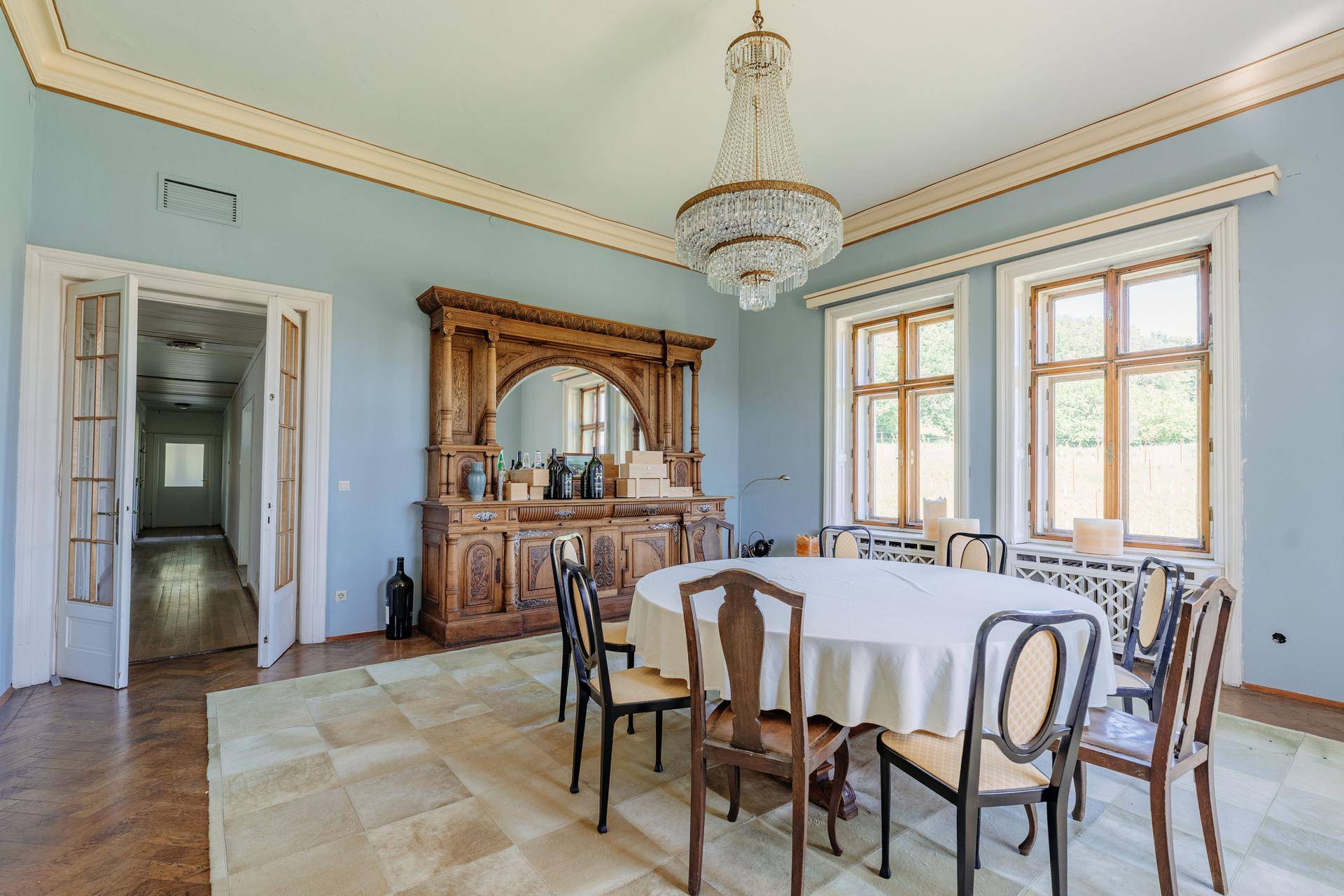 Geräumiger Essbereich mit antikem Sideboard, Kronleuchter und großem Esstisch.