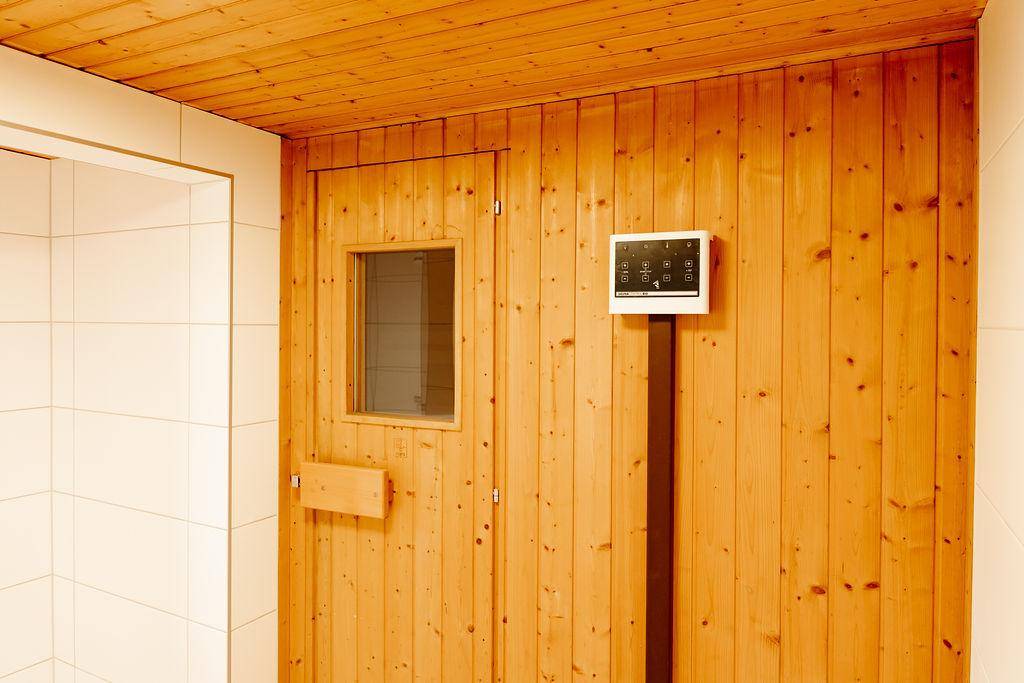 Eingang zu einer Holzsauna mit Steuerungspanel und Holzwänden.