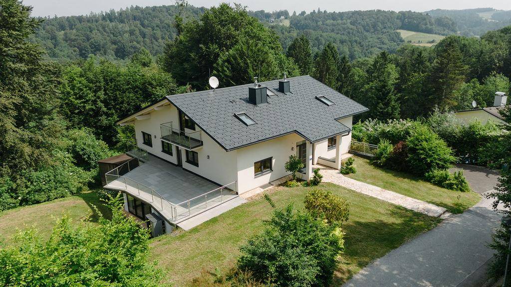 Neubau-Einfamilienhaus in idyllischer Hügellandschaft mit weitläufigem Grundstück und viel Grün.