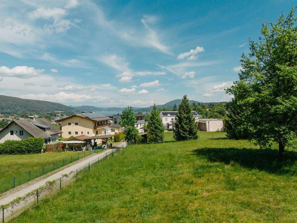 Weitläufige Grünfläche mit Blick auf umliegende Häuser und einen See am Horizont.