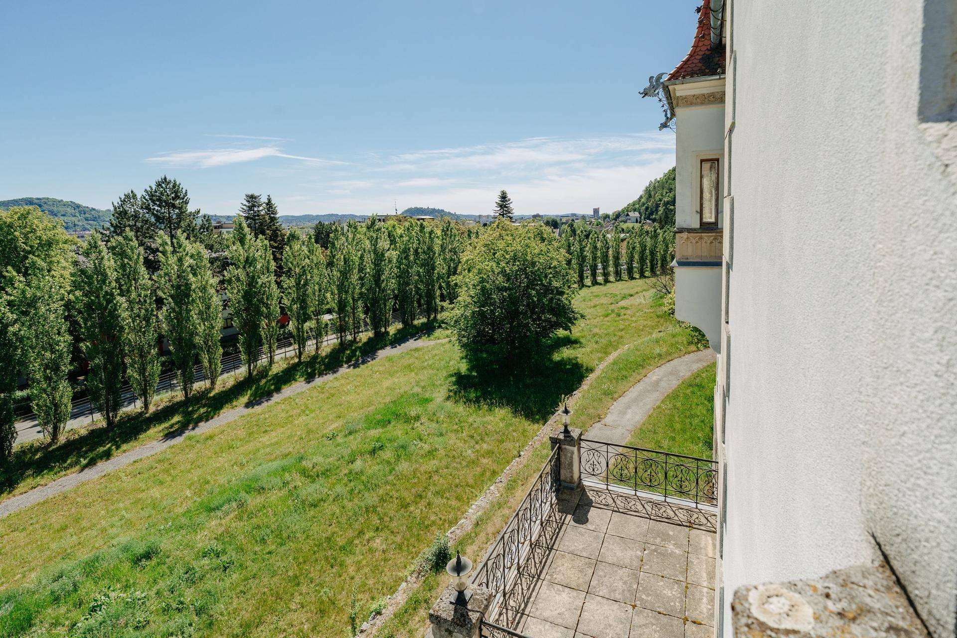 Kleine Terrasse mit schmiedeeisernem Geländer und weitem Blick ins Grüne.