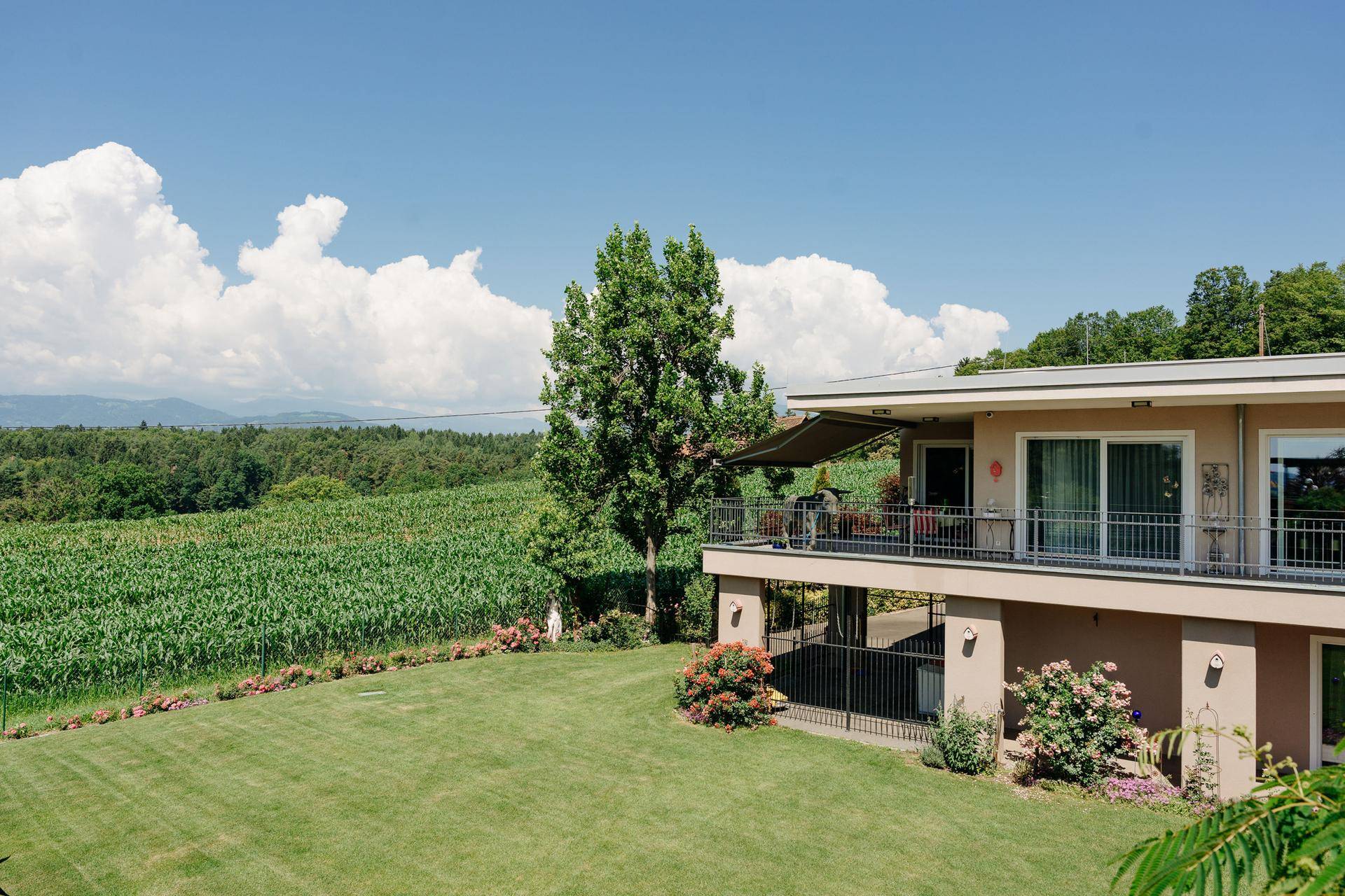 Gebäudefassade mit Balkon und weitem Blick über grüne Felder und die umliegende Landschaft.