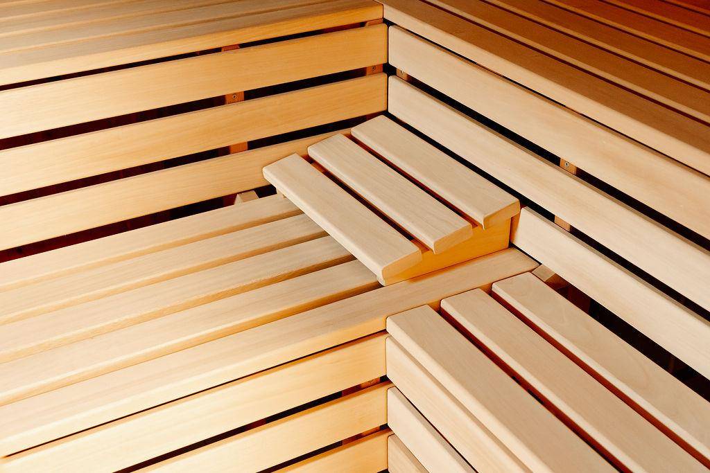 Innenansicht einer Holzsauna mit bequemen Sitzbänken aus hellem Holz.