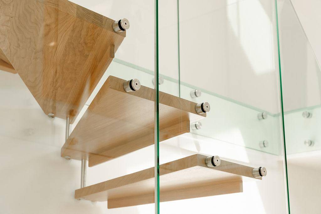 Moderne Treppe mit Holzstufen und eleganten Glasgeländern in einem hellen Innenraum.