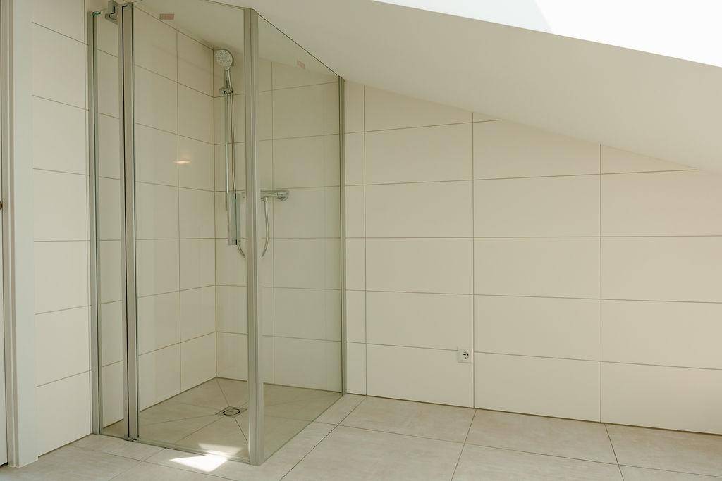 Geräumige Dusche mit Glasabtrennung und hellen Fliesen in einem modernen Badezimmer.
