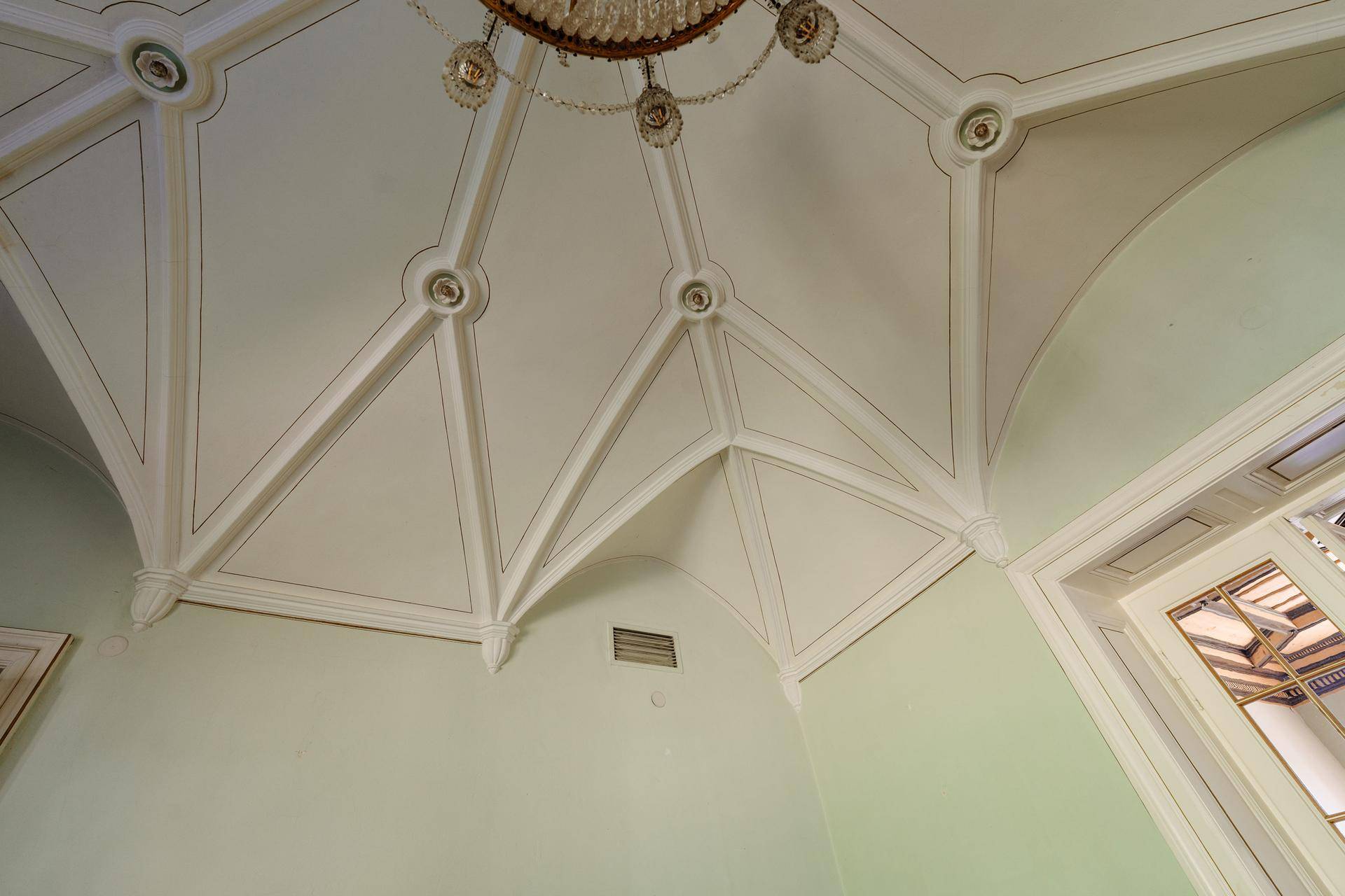 Detailaufnahme einer hohen Decke mit aufwendigen Stuckverzierungen und eleganten Linien.