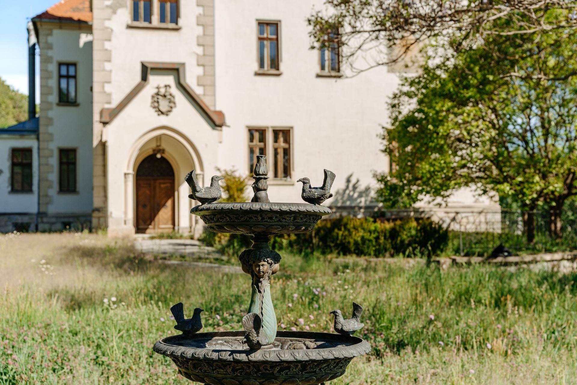 Dekorativer Brunnen im Gartenbereich vor dem historischen Gebäude.