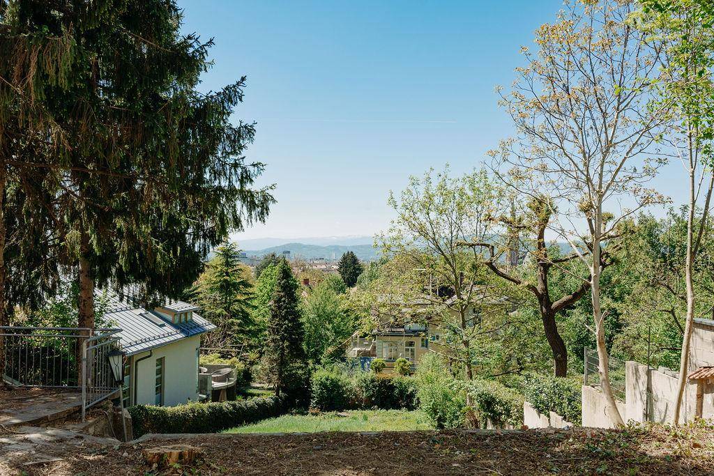 Terrassierter Gartenbereich mit Bäumen und weitem Blick über die grüne Landschaft.