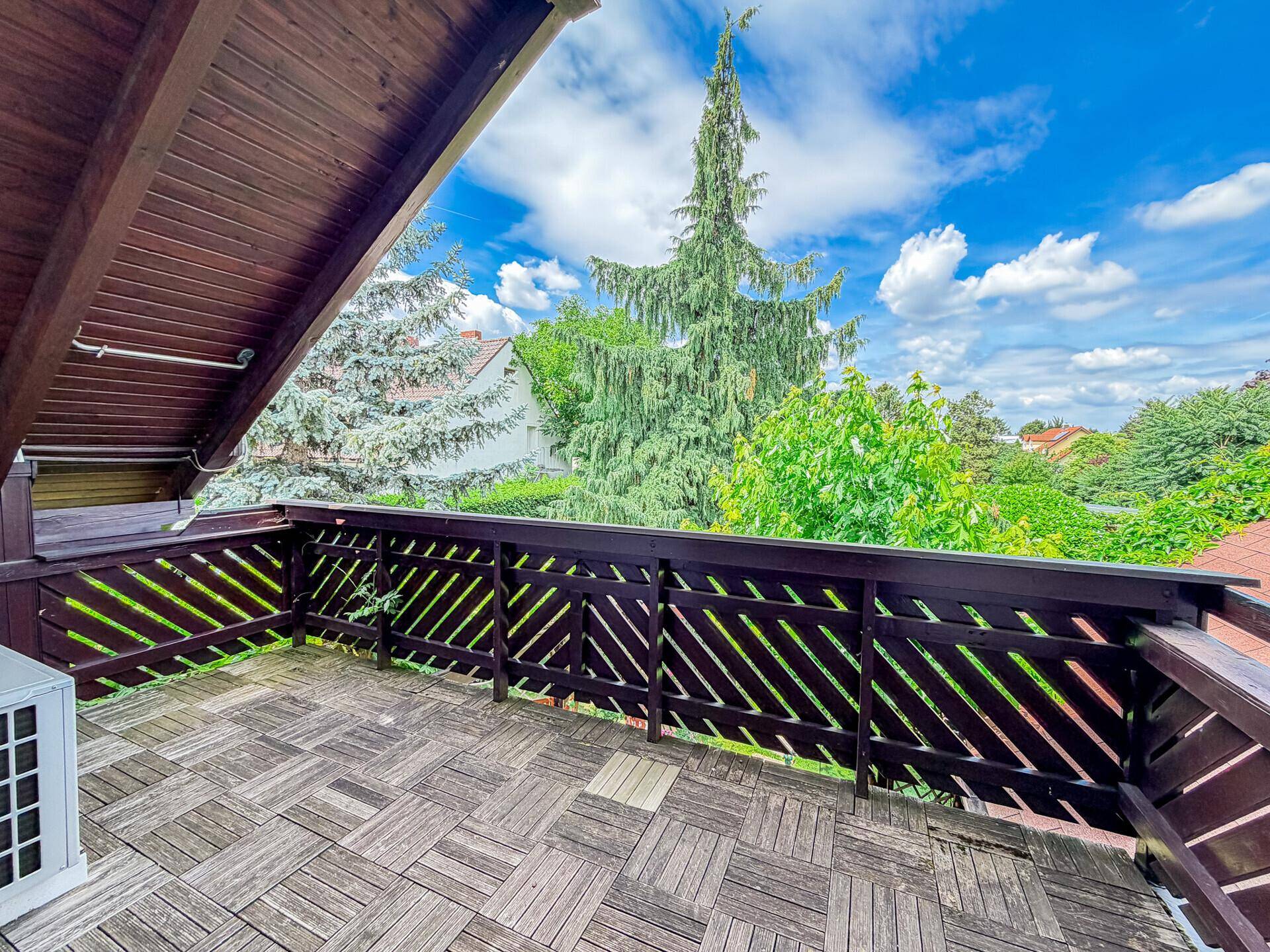 Geräumiger Balkon mit Holzboden und Blick ins Grüne.