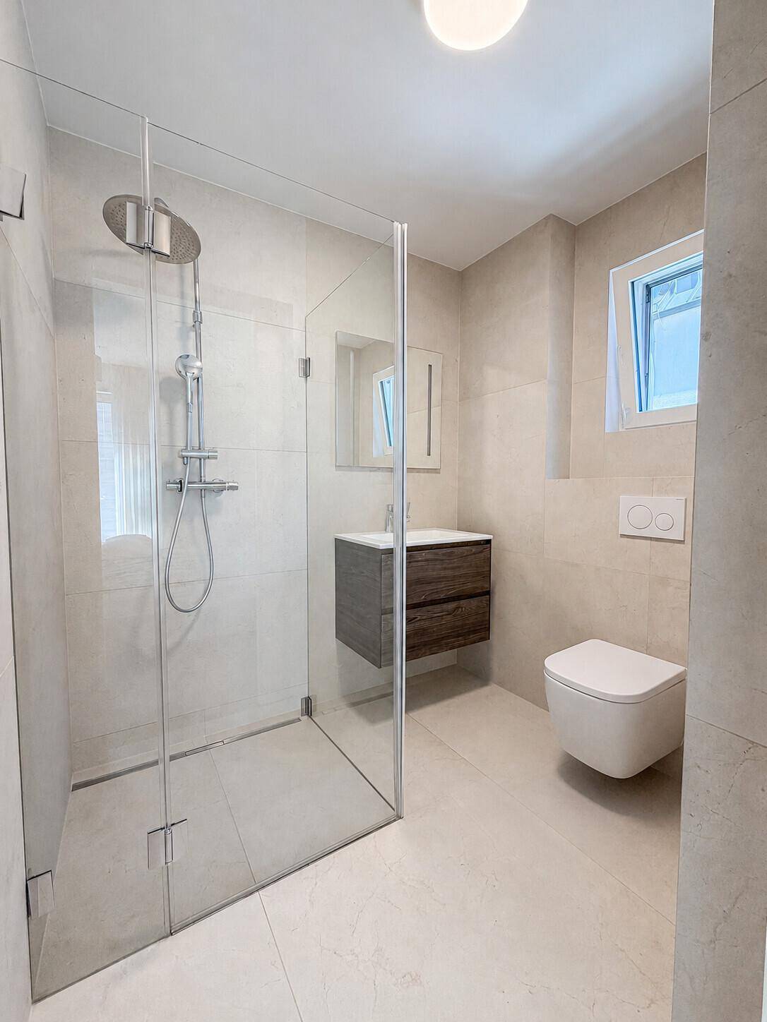 Modernes Badezimmer mit begehbarer Dusche, wandhängendem WC und Fenster.
