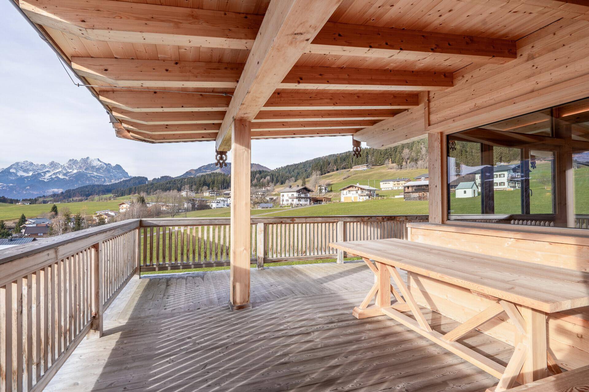 Großer Holzbalkon mit Esstisch und beeindruckendem Panoramablick auf die umliegende Bergwelt.