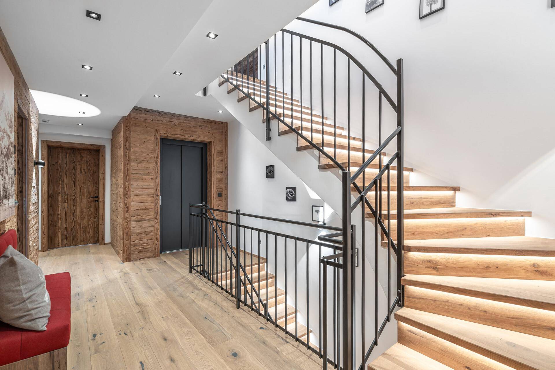 Elegantes Treppenhaus mit Holzstufen, Metallgeländer und integriertem Aufzug für Komfort.