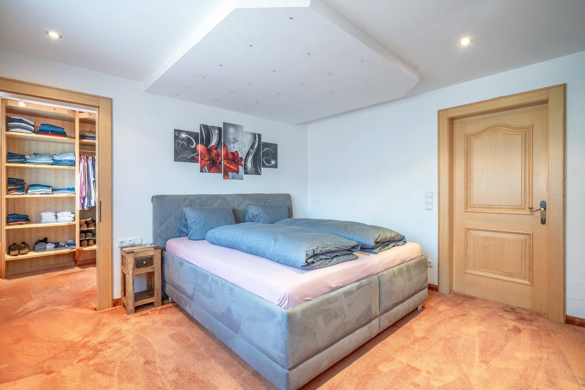 Geräumiges Schlafzimmer mit Doppelbett, Teppichboden und integriertem begehbarem Kleiderschrank.