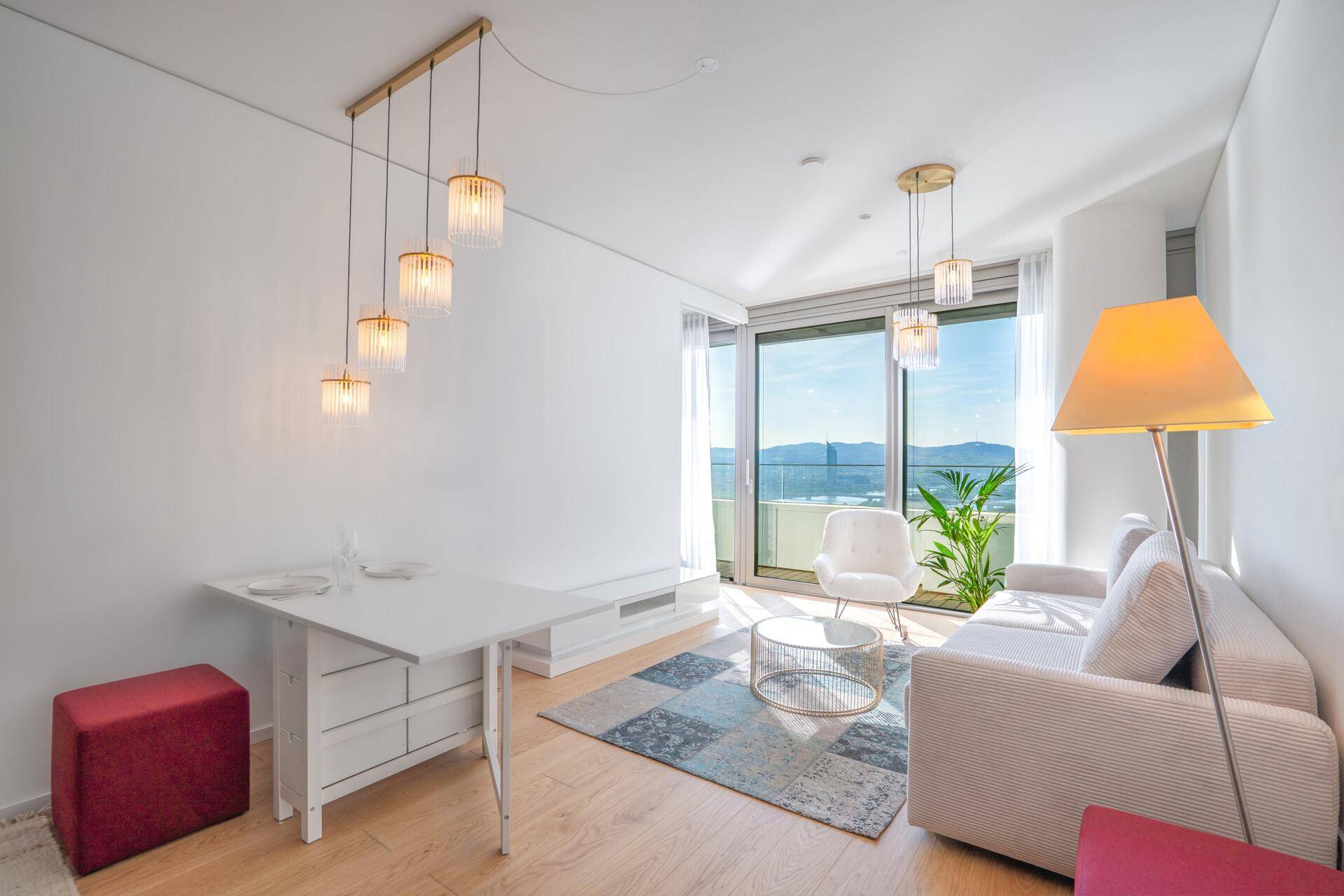Helles Wohn- und Esszimmer mit modernem Mobiliar, Holzboden und Zugang zu einem Balkon mit Aussicht.
