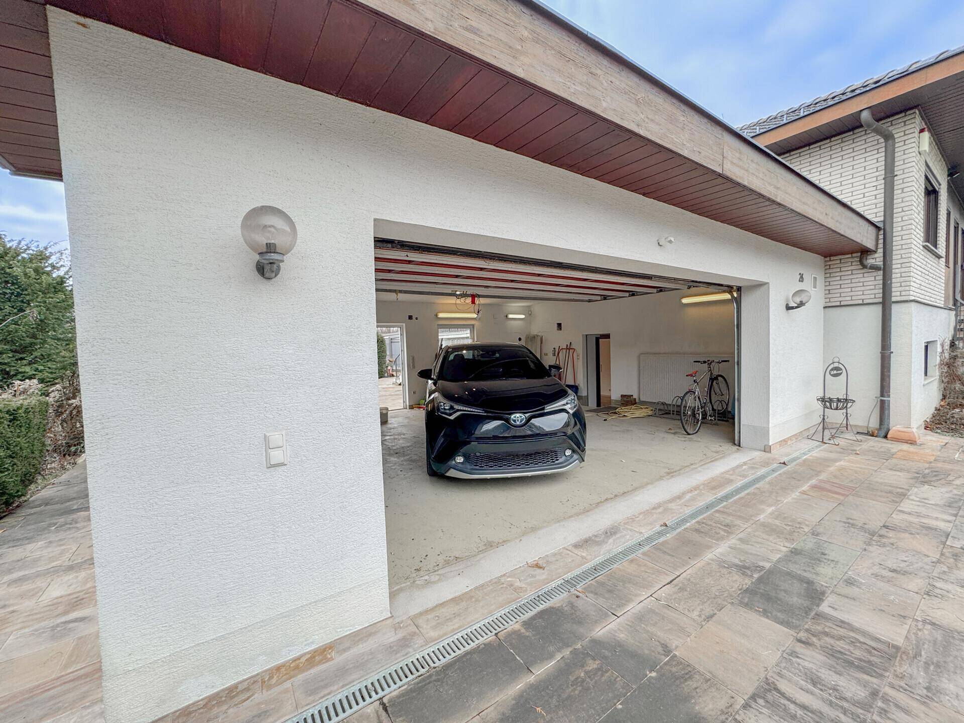 Geräumige Doppelgarage mit Stellplatz für ein Fahrzeug und einer gepflasterten Zufahrt.
