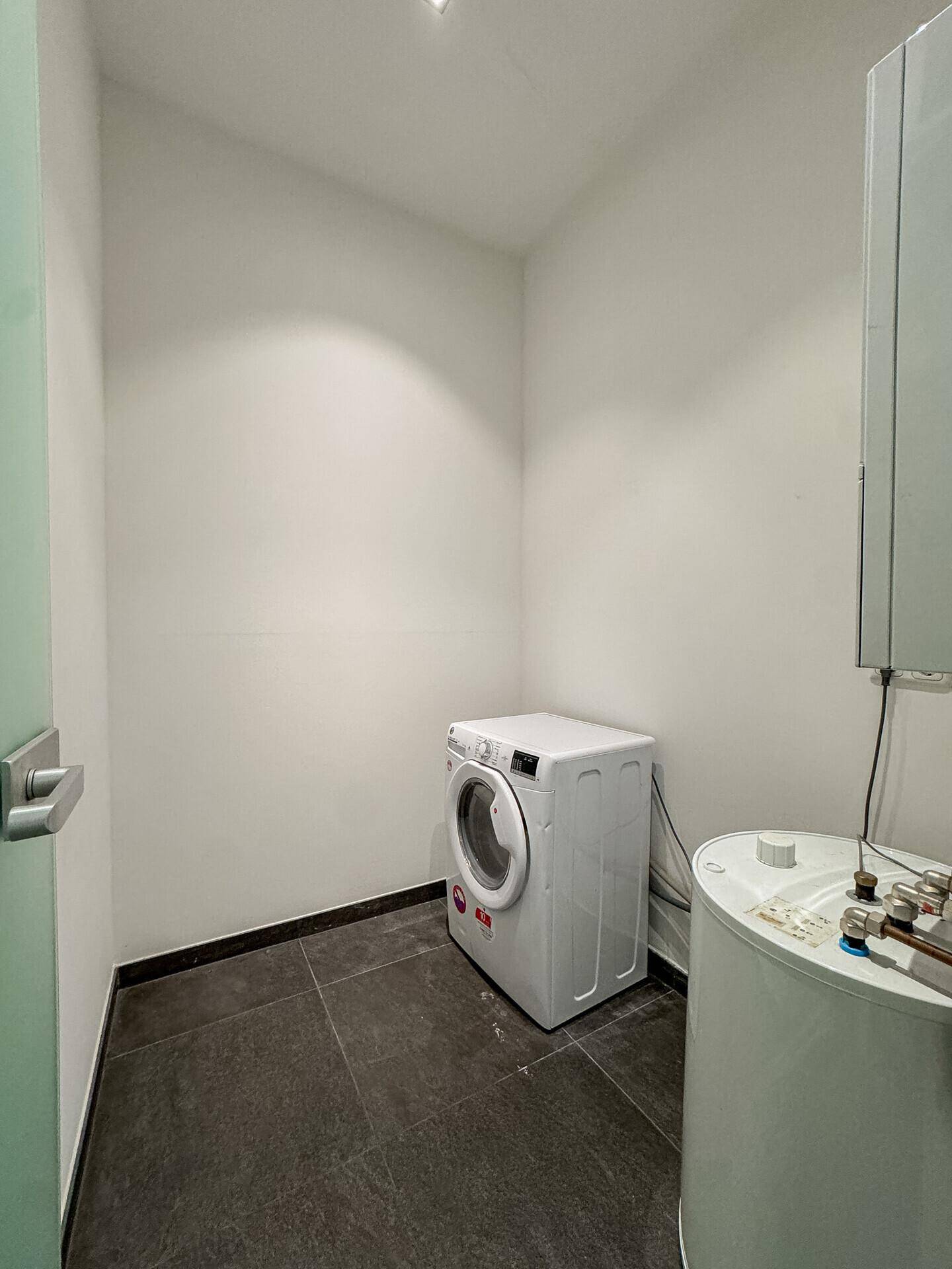Praktischer Hauswirtschaftsraum mit Waschmaschine und Warmwasserbereiter, ideal für den täglichen Gebrauch.