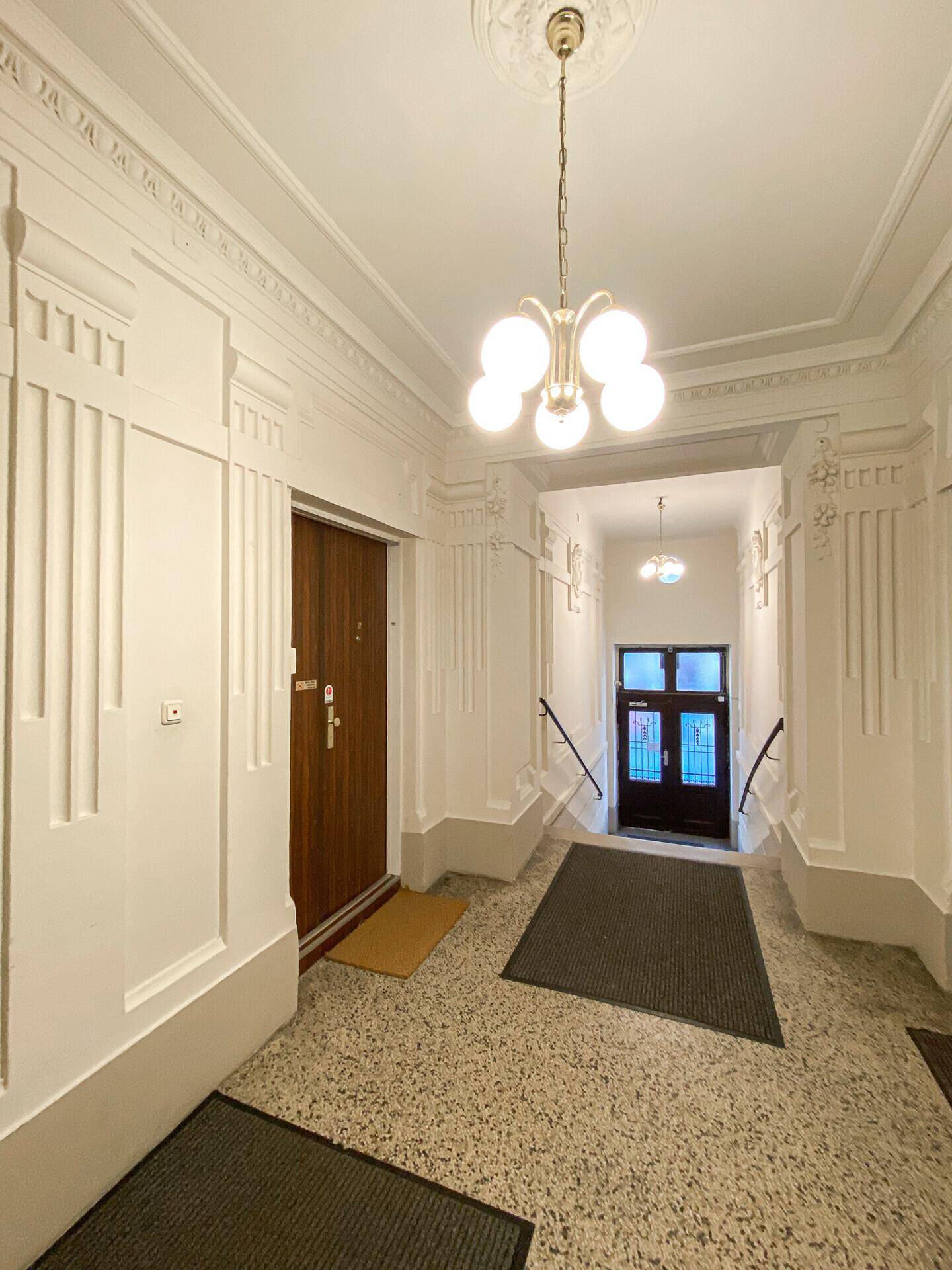 Eleganter Eingangsbereich mit dekorativen Wänden, Terrazzoboden und Kronleuchter.