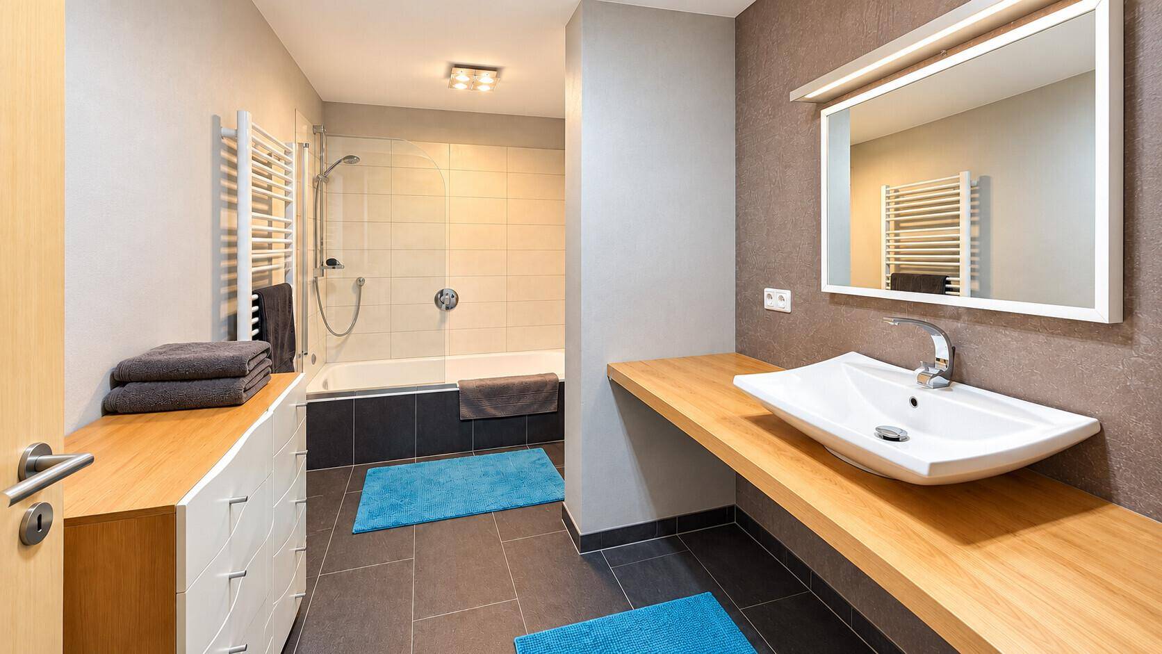 Modernes Badezimmer mit Dusche, Badewanne, Einzelwaschbecken und beheiztem Handtuchhalter.