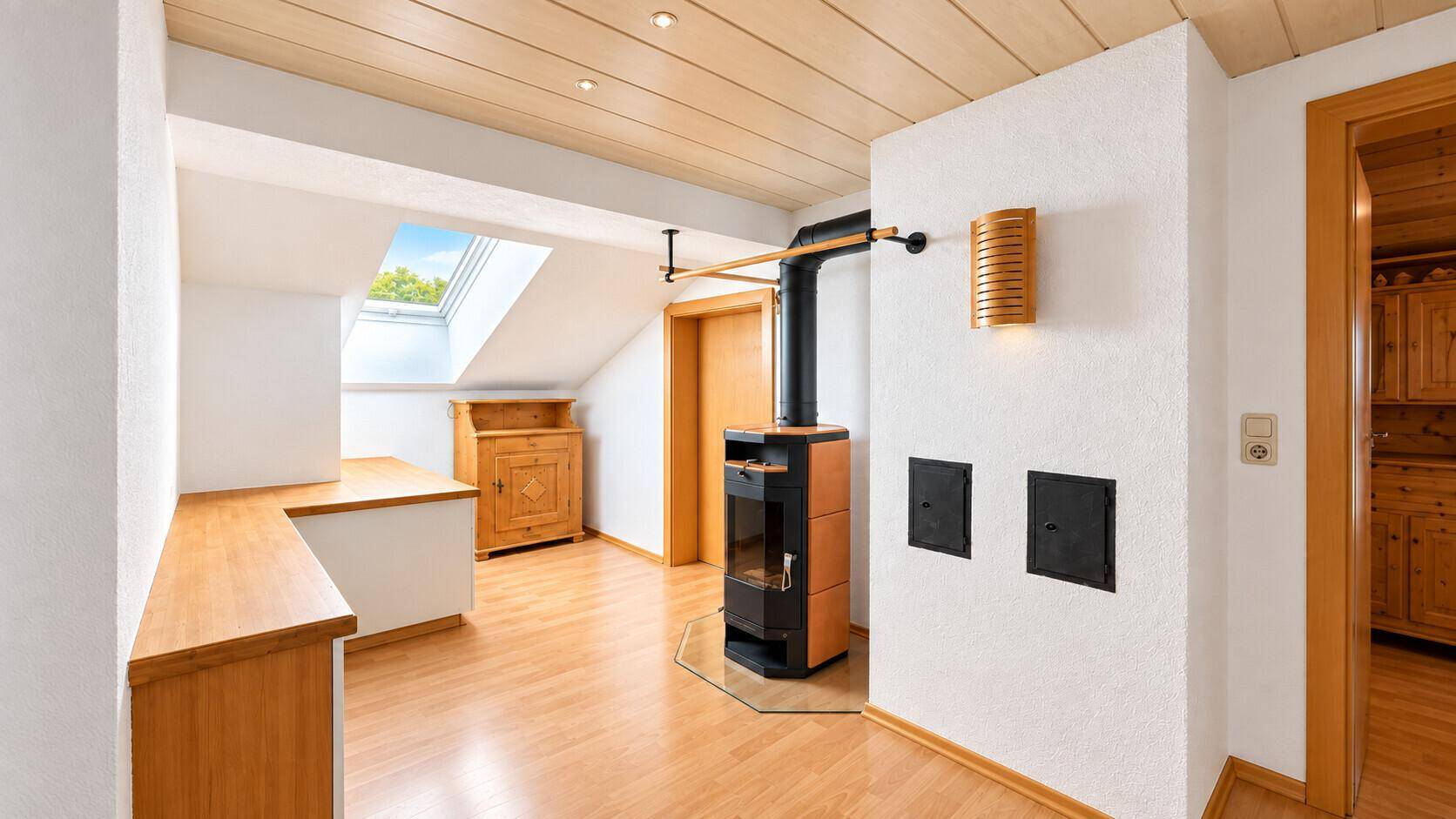 Heller Flur mit Holzbalkendecke, Kaminofen und Dachfenster für natürliches Licht.