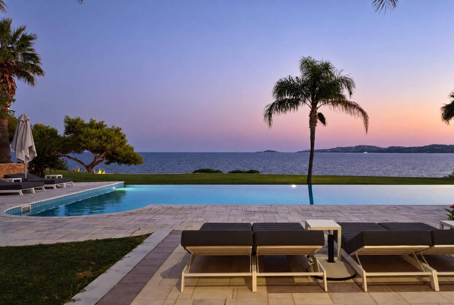 Atemberaubender Infinity-Pool bei Sonnenuntergang mit Blick auf das ruhige Meer und die Küste.