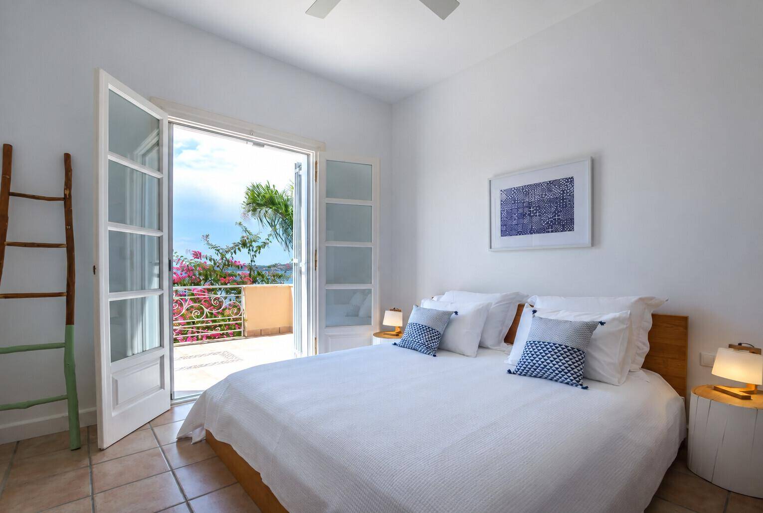 Helles Schlafzimmer mit Doppelbett, Deckenventilator und direktem Zugang zu einem Balkon mit Aussicht.