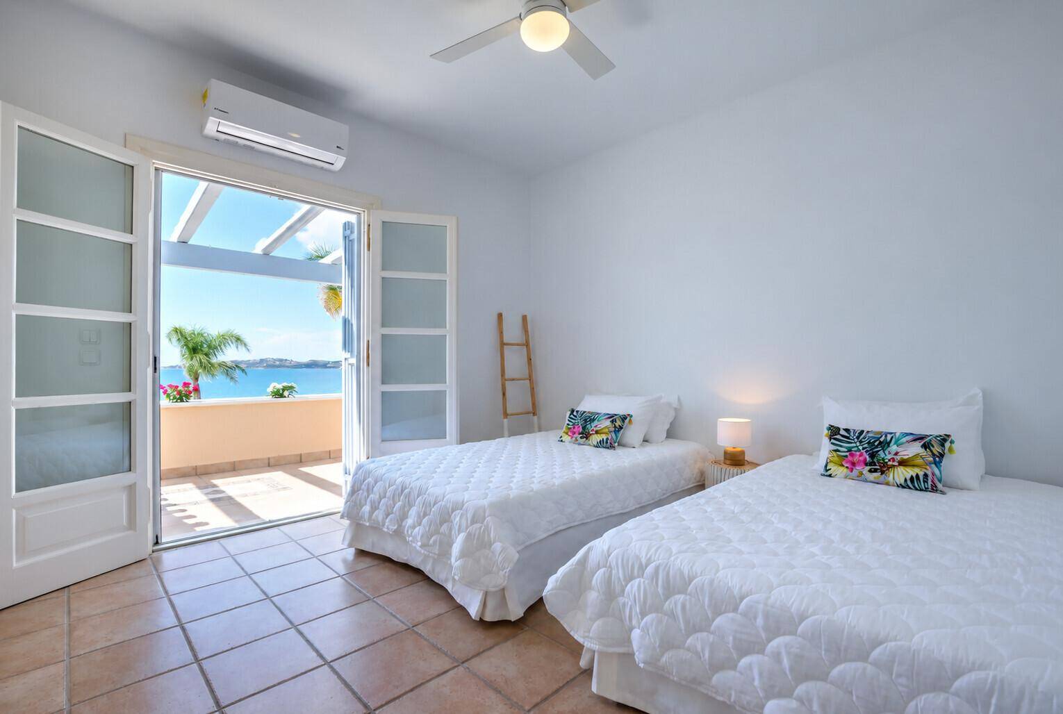 Freundliches Schlafzimmer mit zwei Einzelbetten, Klimaanlage und Balkonzugang mit Meerblick.