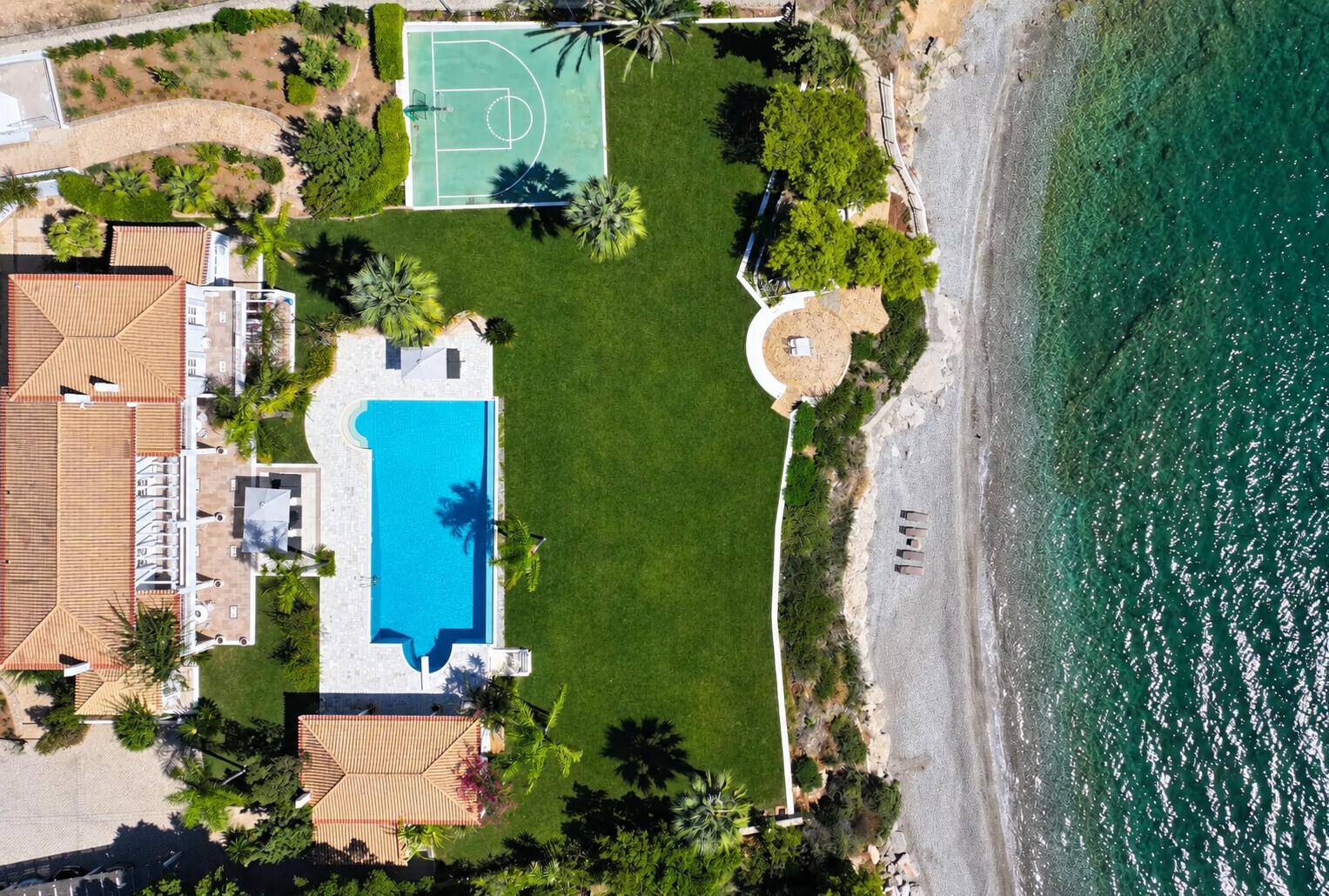 Luftaufnahme des weitläufigen Anwesens mit Villa, Pool, Sportplatz, Garten und privatem Strandzugang.
