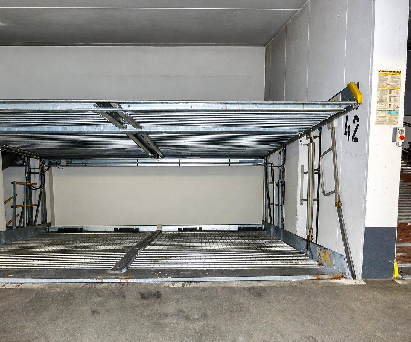 Ein doppelter Parklift in einer Tiefgarage, bereit für die Aufnahme von Fahrzeugen auf zwei Ebenen.