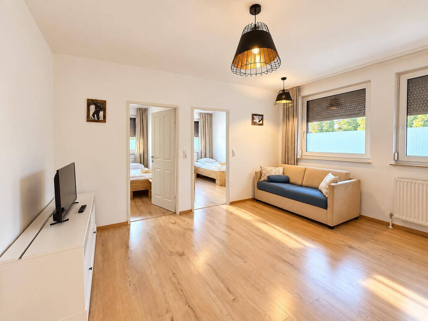 Geräumiger Wohnbereich mit Sofa, Fernseher und Zugang zu weiteren Zimmern.