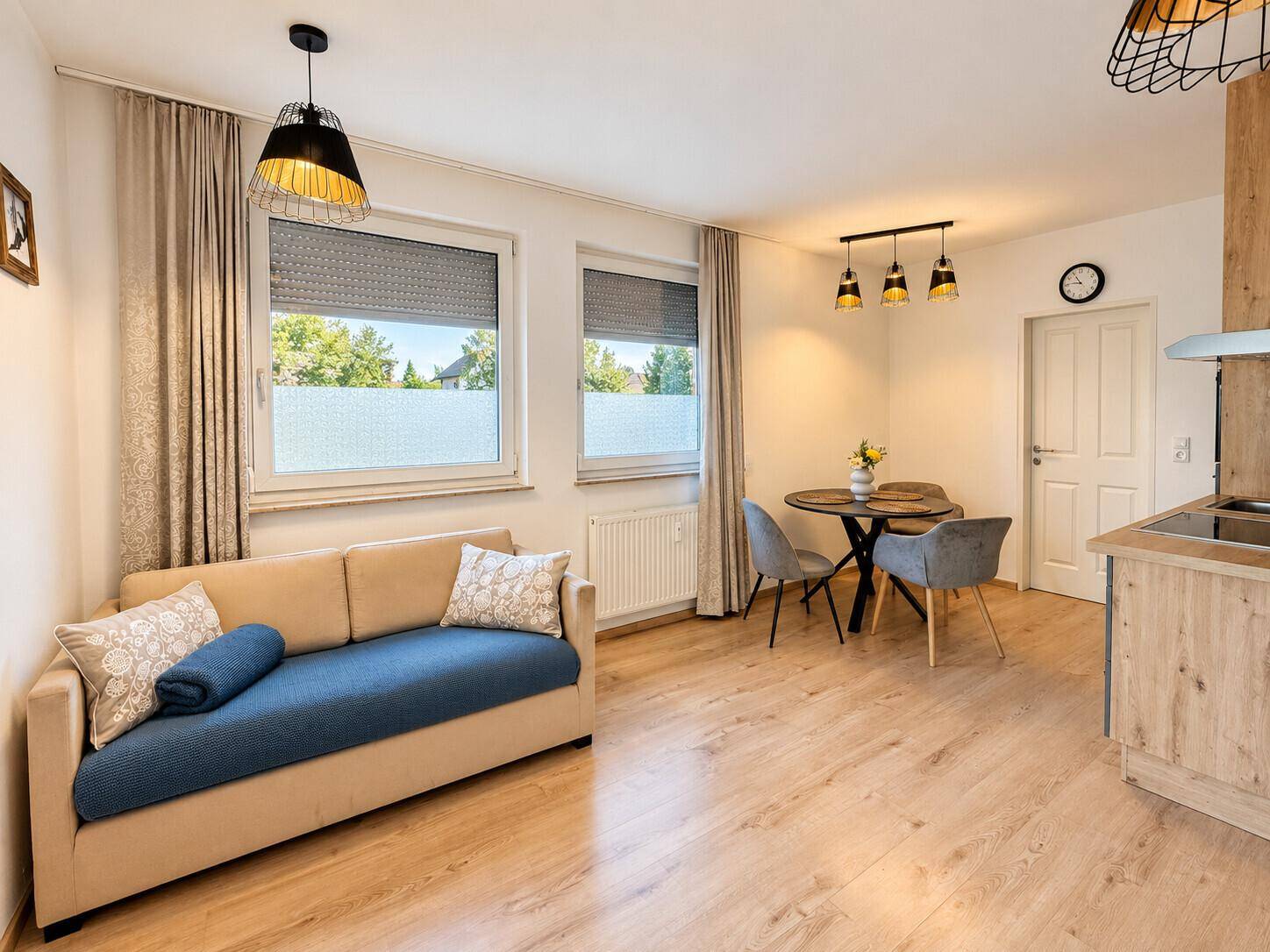 Gemütlicher Wohn-Essbereich mit Sofa, Esstisch und Blick nach draußen durch die Fenster.