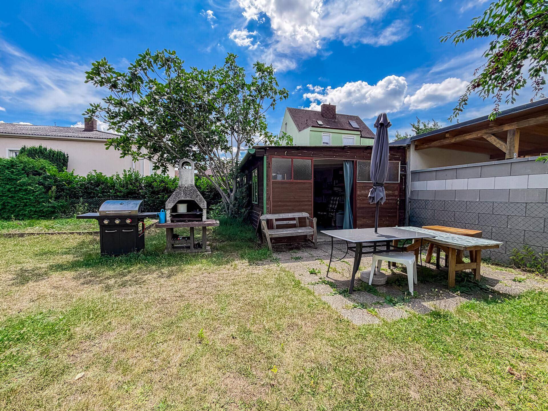 Gemütlicher Gartenbereich mit Gartenhaus, Grill und Sitzgelegenheiten für entspannte Stunden im Freien.