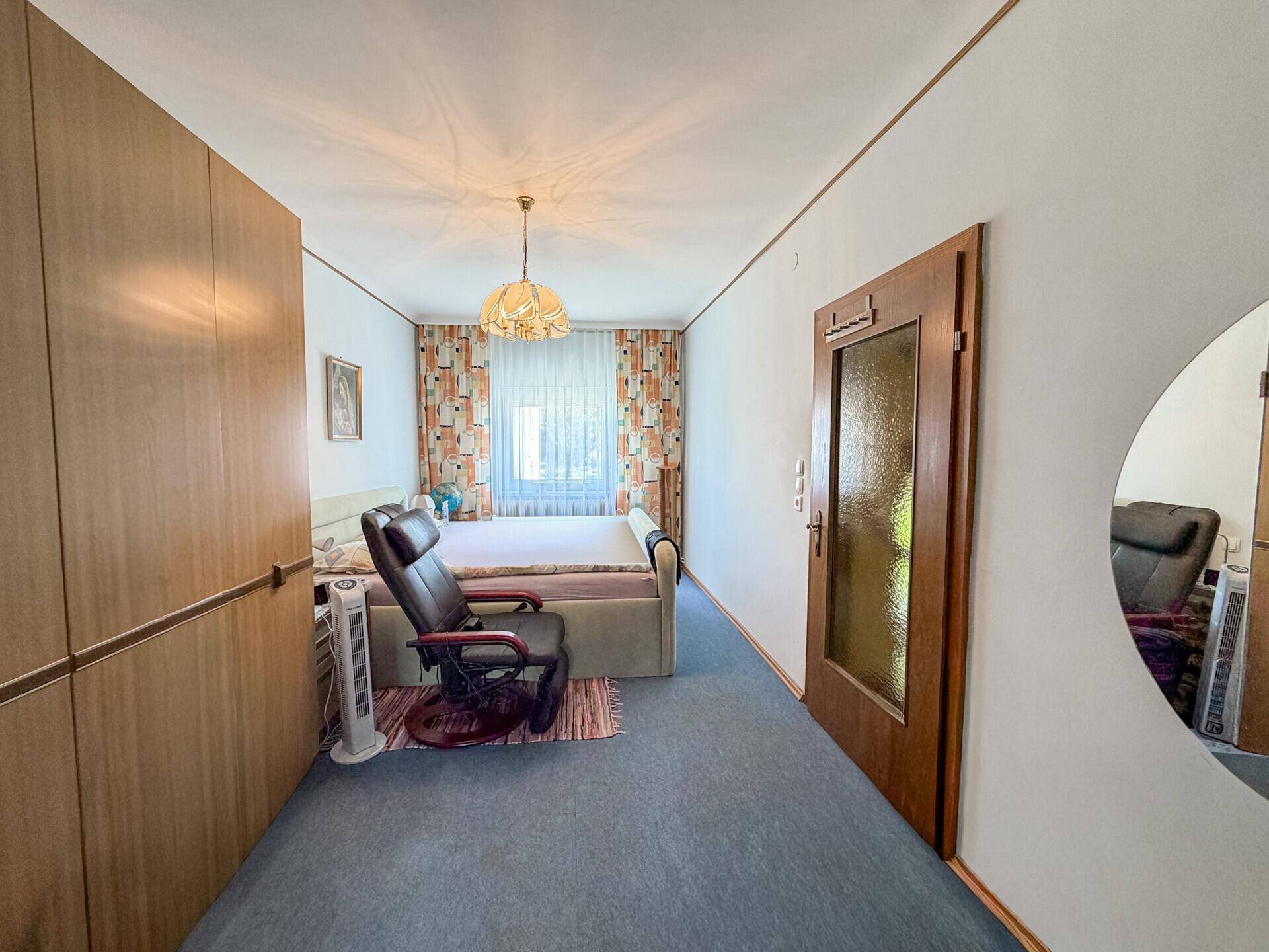 Helles Schlafzimmer mit Teppichboden, großem Kleiderschrank und Fenster.