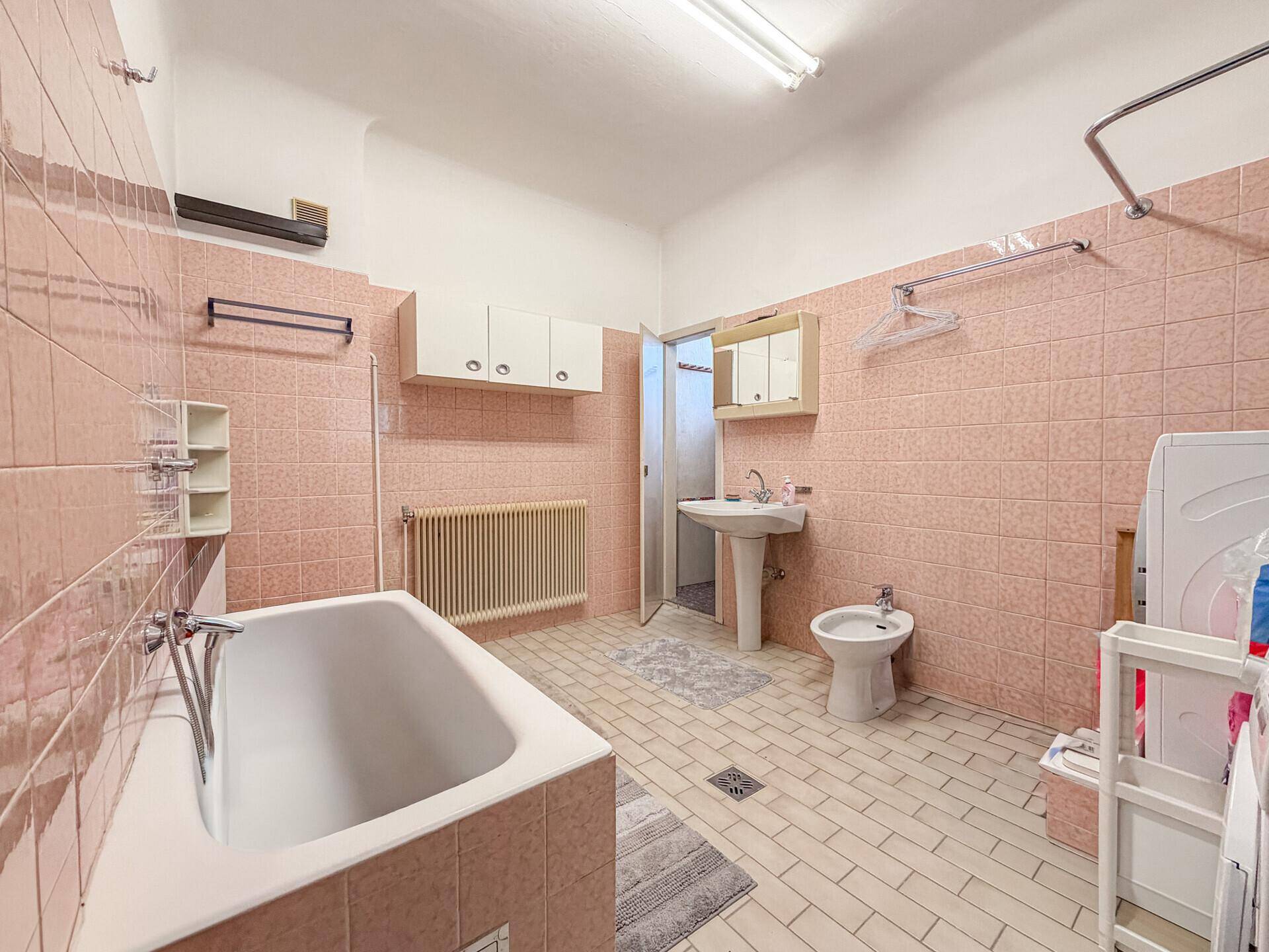 Badezimmer im Stil der 80er Jahre mit rosa Fliesen, Badewanne und Bidet.