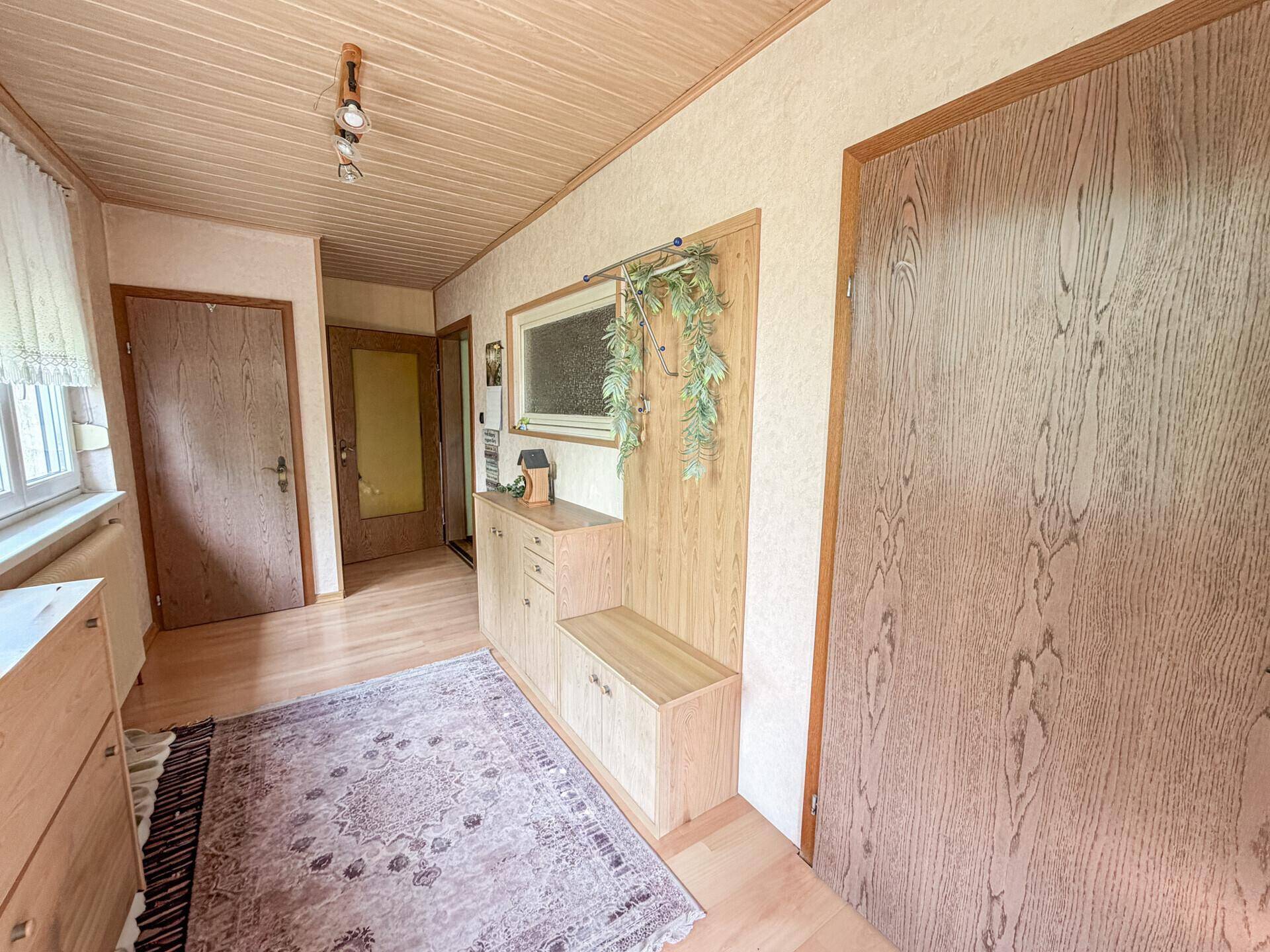 Heller Flur mit Holzvertäfelung an der Decke und praktischen Einbaumöbeln.