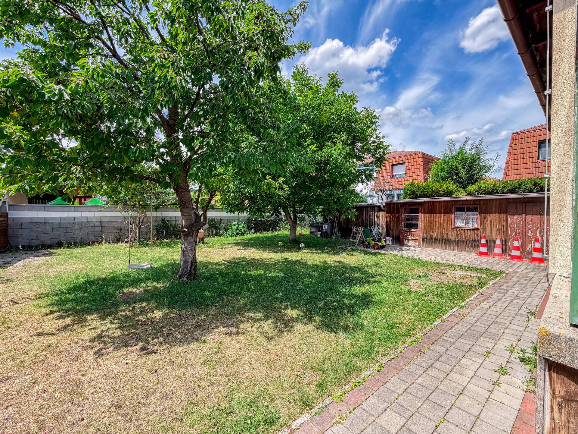 Sonniger Garten mit altem Obstbaum und Rasenfläche, ideal zum Spielen und Entspannen.