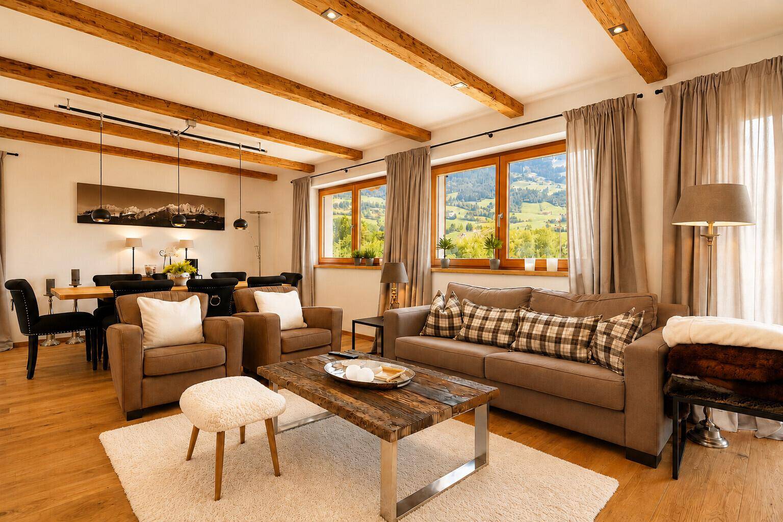 Heller Wohnbereich mit bequemen Sofas, Holzbalken und Panoramablick auf die grüne Landschaft.
