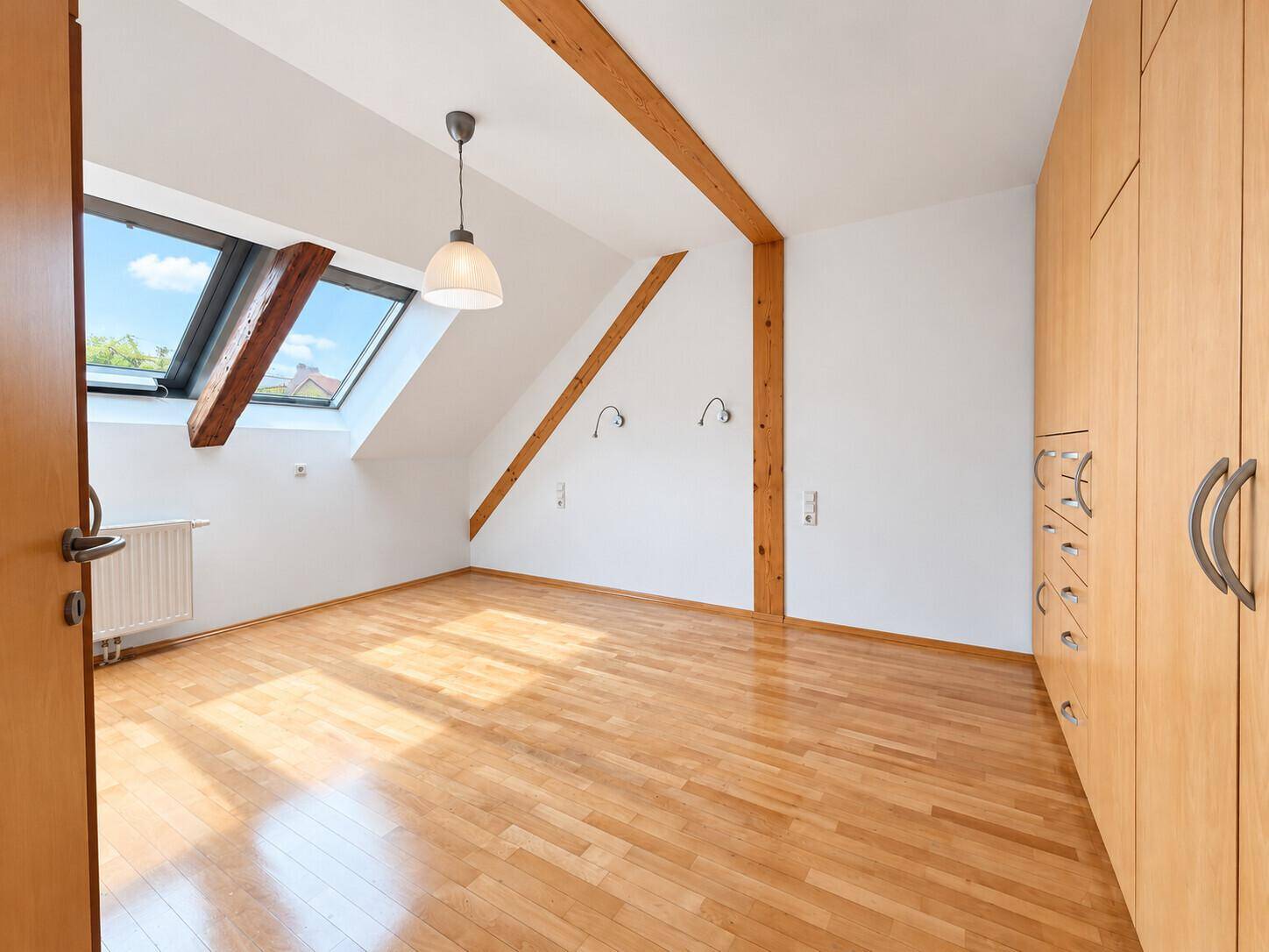 Geräumiges Schlafzimmer mit Holzbalken, Parkettboden und integriertem Kleiderschrank.