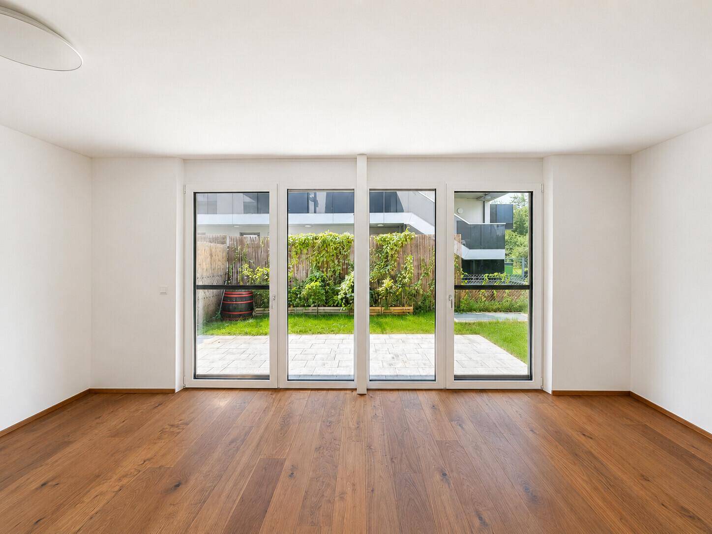 Lichtdurchfluteter Raum mit großen Fenstern und direktem Zugang zur Terrasse und Garten.