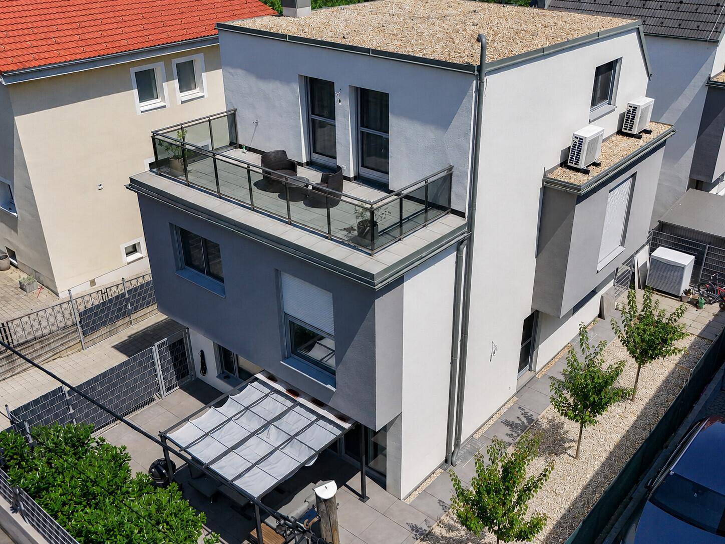 Luftaufnahme des modernen Hauses mit Flachdach, Balkon und Gartenbereich.