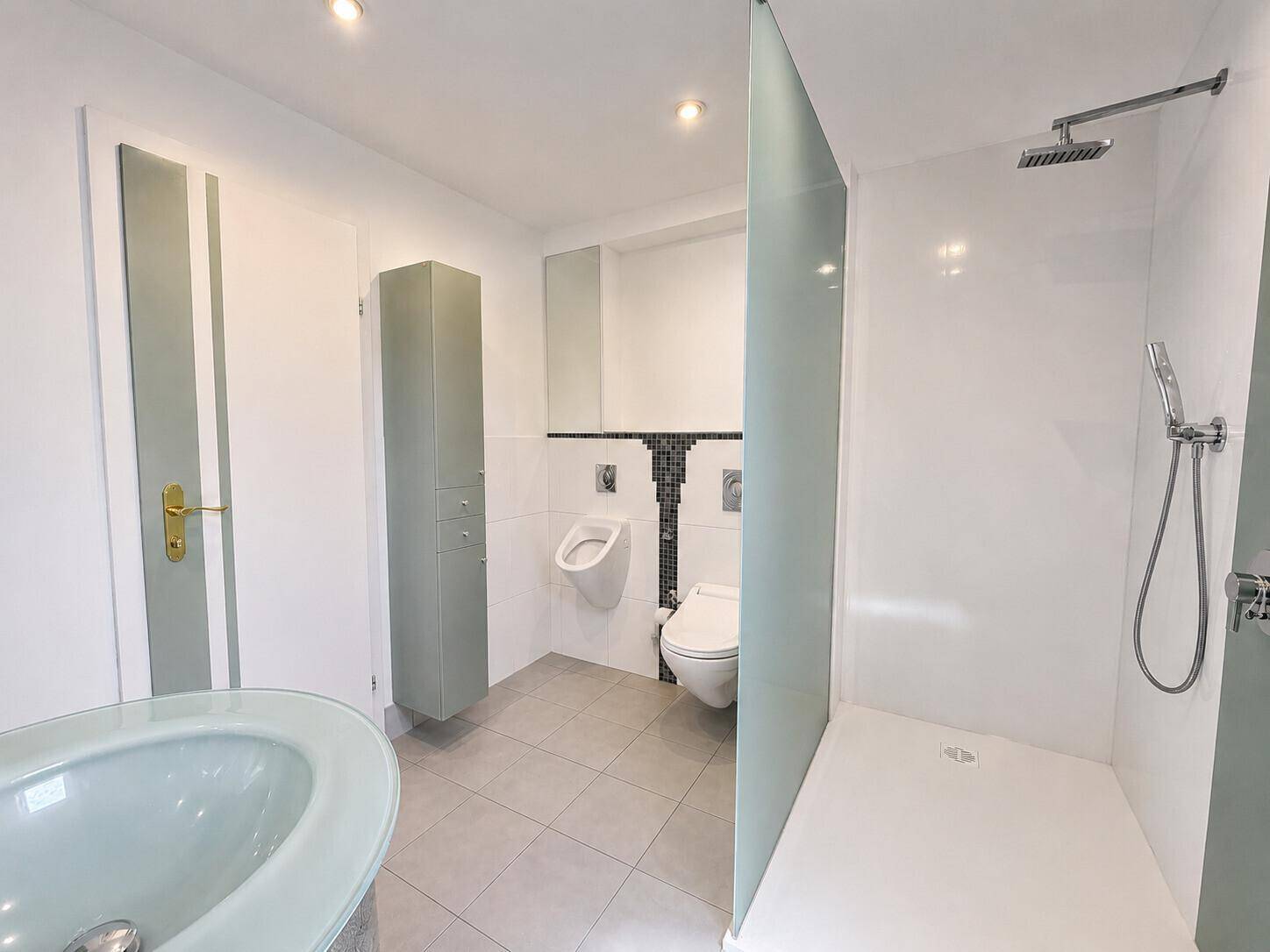 Helles Badezimmer mit begehbarer Dusche, Urinal und modernem Design.