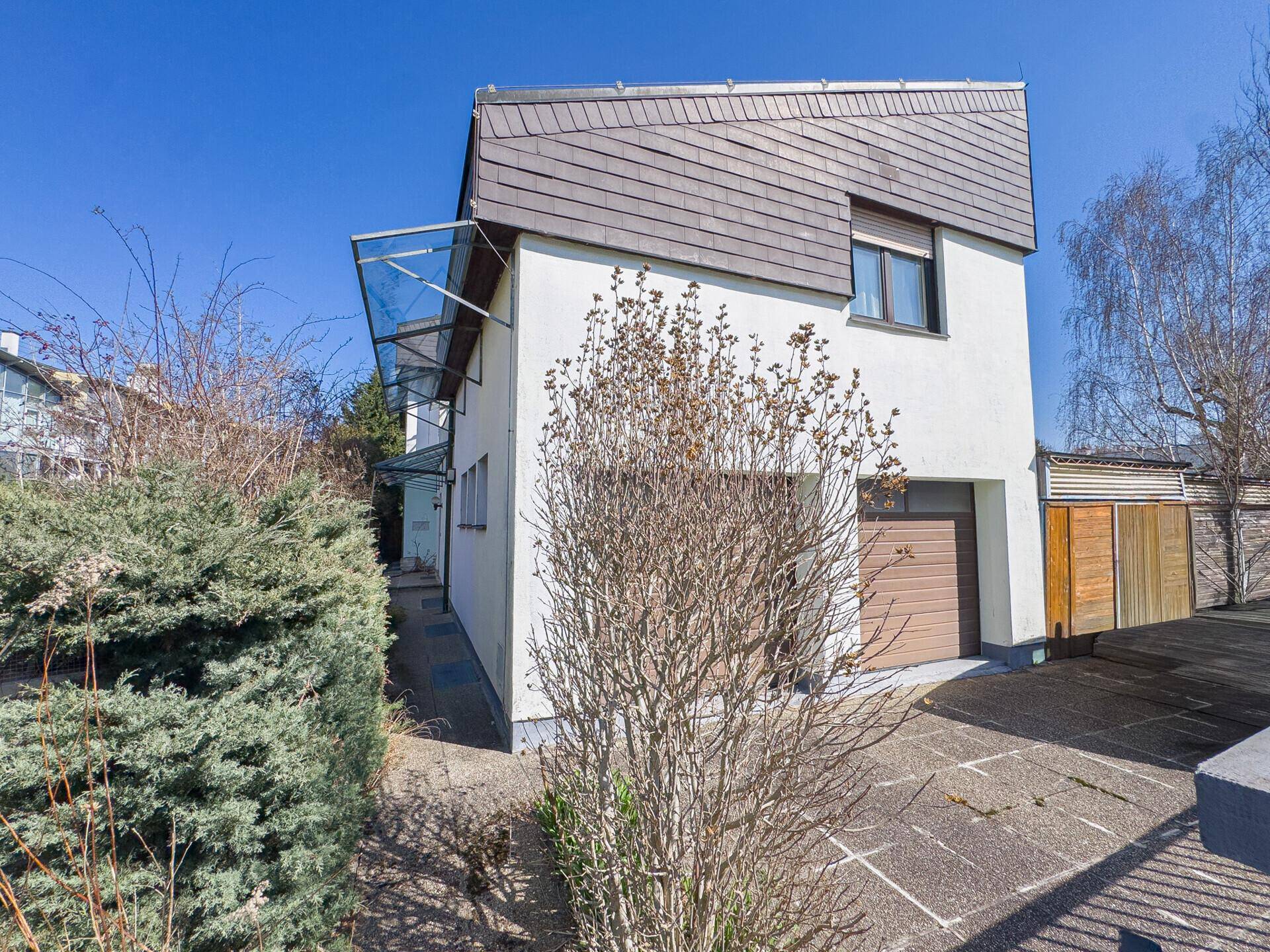 Seitenansicht des Hauses mit einer Garage und einem markanten Schindeldach.